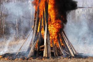 Bonfire of wooden boards and car tires, flame of red fire, curling black smoke photo