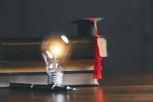 Light bulbs and books with graduation hat. Concept of reading books, knowledge, and searching for new ideas. Innovation and inspiration, Creativity with twinkling lights, the inspiration of ideas. photo