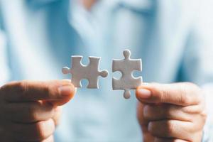 Business woman person hand holding puzzle piece idea for strategy and solution. Closeup part of two white jigsaw connect together. Concept of join cooperation success teamwork-problem corporate team photo