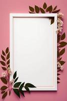 Empty white frame on pink background with flowers and leaves on the corner photo