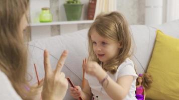 inteligente pequeño niña es jugando cerebro teasers con su madre. el pequeño niña es jugando un cerebro juego y su madre es acompañamiento su. video