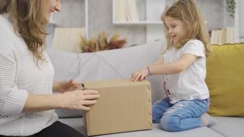 Mother gives dolls to her little daughter. Mother gives dolls out of boxes to her little daughter. video