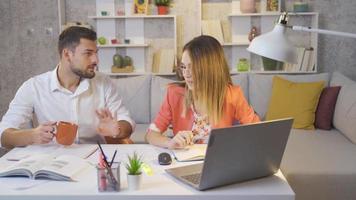 Her husband helps the woman who is struggling with her job. The woman working in the home office struggles with her work and her husband comes to help her. video