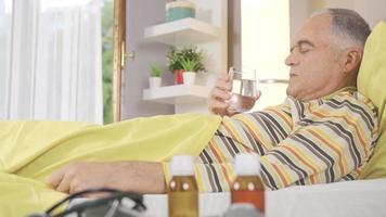 Sick old man drinking water in bed. Sick man lying in bed drinking water. video