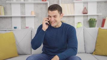 Happy man talking on the phone at home. The man is making pleasant phone calls at home. video