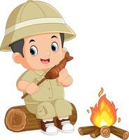 an adventurous boy sits on a fallen tree and is eating grilled fish in front of a bonfire vector