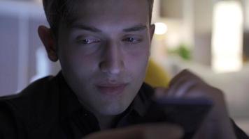 Writing and texting on mobile phone screen. Hand of man texting, using smartphone in living room at home. video