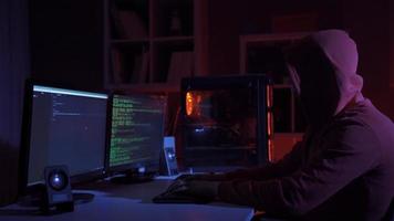 kant visie van hacker zittend in de buurt computer monitoren met groen code schermen. eenzaam hacker programmeur omringd door programmering codes koppel in een donker milieu cyberruimte. video