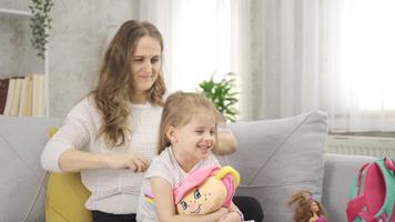 Mom is combing her cute beautiful daughter's hair. The mother is combing the blonde girl's hair. video