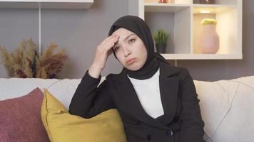 muçulmano mulher vestindo uma lenço de cabeça tem uma dor de cabeça. muçulmano mulher às casa tendo uma dor de cabeça e fricção dela cabeça. video