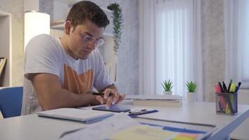 Man doing calculations on papers. Man doing calculations on phone at his desk. Takes notes on paper. video