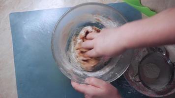 Female hand kneads the dough for making homemade cookies in a glass bowl, top view video