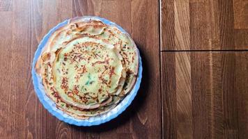 delizioso Pancakes con aggiunto erbe aromatiche siamo dire bugie su un' piatto su il di legno cenare tavolo. video