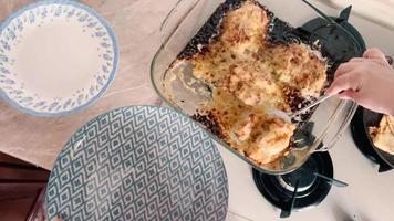 A woman is putting freshly cooked fried meat into plates. video