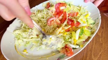 Mixing salad with fresh vegetables, tomatoes, peppers, cucumbers, cabbage, and eggs using a spoon. video