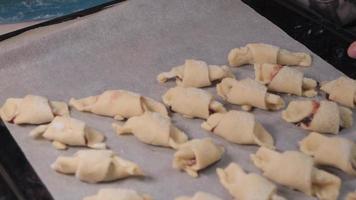 vrouwen handen leggen rauw koekjes voor bakken Aan een bakken vel met perkament papier. video