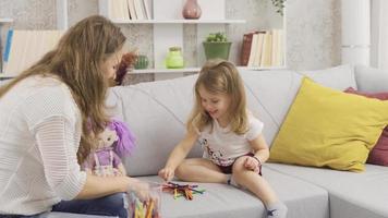 The little girl is playing a game of intelligence and her mother is helping her. They play games at home with the mother and her little daughter and are happy. video