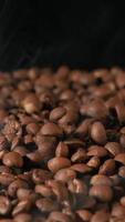 Vertical slow motion of roasted coffee beans falling. Organic coffee seeds. video