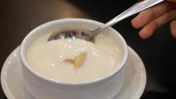 close up to white creamy soup in small soup bowl while using spoon to scooping out for eating
