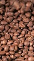 Vertical slow motion of roasted coffee beans falling. Organic coffee seeds. video