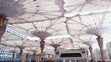 Medina, Saudi Arabia, 2022 - Umbrella construction on the square of Al-Masjid An-Nabawi or Prophet Muhammed Mosque are protecting people from sun at the daytime and works as lights at night video