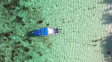 Bird eye drone shot of docking fishing boat near the shore at Anse forbans beach, 3 girls playing in the ocean, Mahe Seychelles video