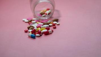 kleurrijke pillen die op roze achtergrond morsen video