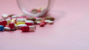 colorful pills spilling on pink background
