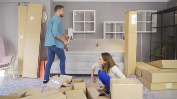 sorridente jovem casal mover para dentro uma Novo casa sentado em chão e desempacotando. uma jovem casal traz caixas para uma Novo plano e elas pegue para trabalhar. video