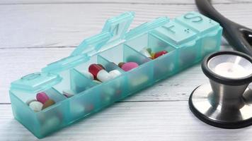 Close up of colorful pills in a container and stethoscope on white background video