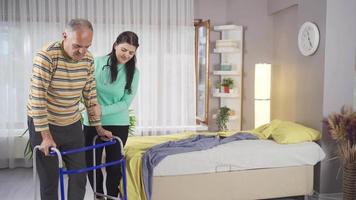 Patient walking with walker and female nurse helping him. A senior man using a walker in a rehab center or nursing home. video