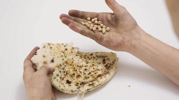 een Mens met kikkererwten in zijn palm en verrot brood in voorkant van hem. voedsel crisis. de hongerig en arm Mens is ervaren financieel en voedsel crises. video