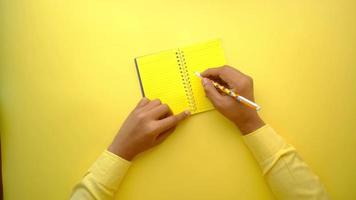 Open book and a pencil on yellow background video
