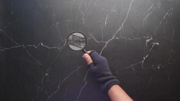 hand holding magnifying glass against marble background video