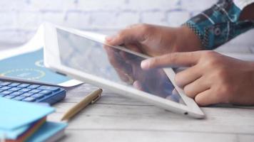 Man's hand working on digital tablet at office desk, using self created chart video