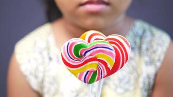 Child girl holding rainbow heart shape lollipop video