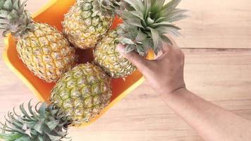 Putting fresh Pineapple in bowl on table video