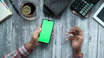 Top view of man hand using smart phone on office desk showing frustration video