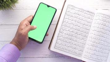 hand- gebruik makend van slim telefoon en heilig boek koran en rozenkrans Aan tafel video