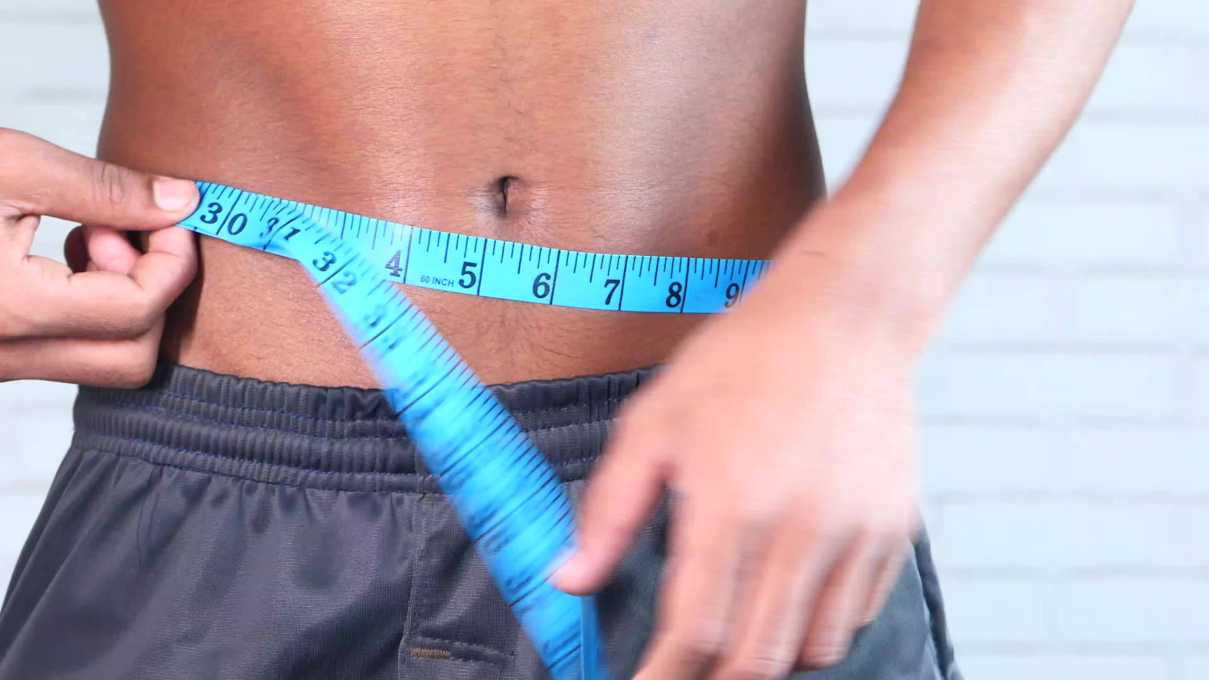 https://static.vecteezy.com/system/resources/thumbnails/021/363/073/original/young-man-measuring-his-waist-with-a-tape-measure-close-up-video.jpg