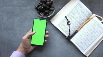 dichtbij omhoog van heilig boek koran en groen scherm smartphone Aan tafel video