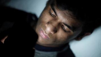 jonge man zittend op bed met behulp van slimme telefoon 's nachts video