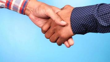Two people hand shake against blue background video