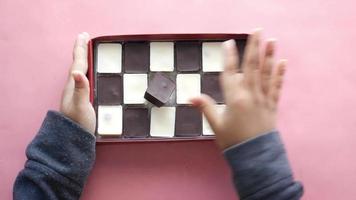 Child hand pick dark and white chocolate in a box video