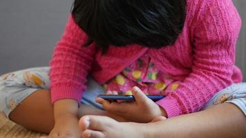 criança menina usando inteligente telefone em mesa enquanto situado video