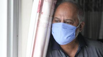 senior man with face mask looking through window video
