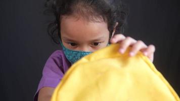 kind meisje met gezicht masker op zoek iets Aan school- zak video