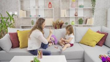 The little girl is playing a game of intelligence and her mother is helping her. They play games at home with the mother and her little daughter and are happy. video