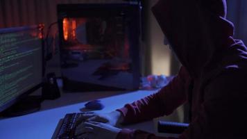 Side view of hacker sitting near computer monitors with green code screens. Lonely hacker programmer surrounded by programming codes interface in a dark environment cyberspace. video