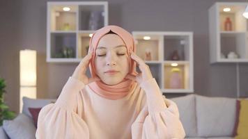 giovane ragazza nel hijab essere infelice e deluso. ragazza nel hijab sembra a libri e il computer portatile nel davanti di sua e è triste. video